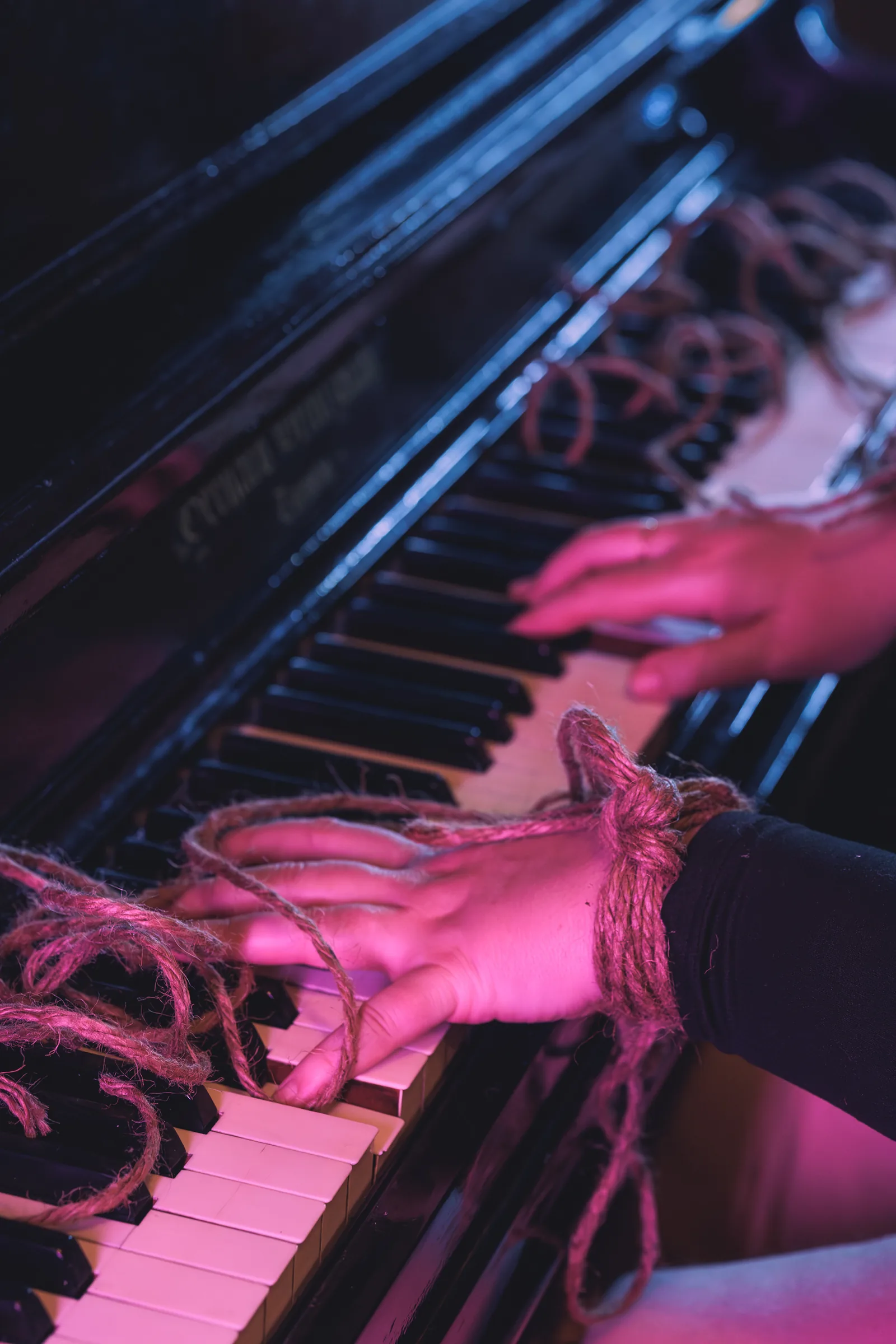 Hands on piano keys with rope detail.